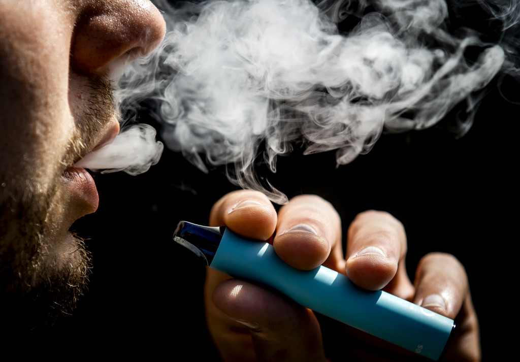 Een jonge man rookt een vaper, oftewel een e-sigaret.
