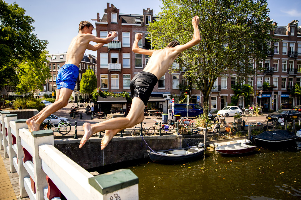 Jongens springen in de Kattensloot in Amsterdam op een bloedhete dag.