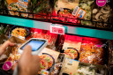 Een klant met een zelfscanner bij supermarkt Albert Heijn.