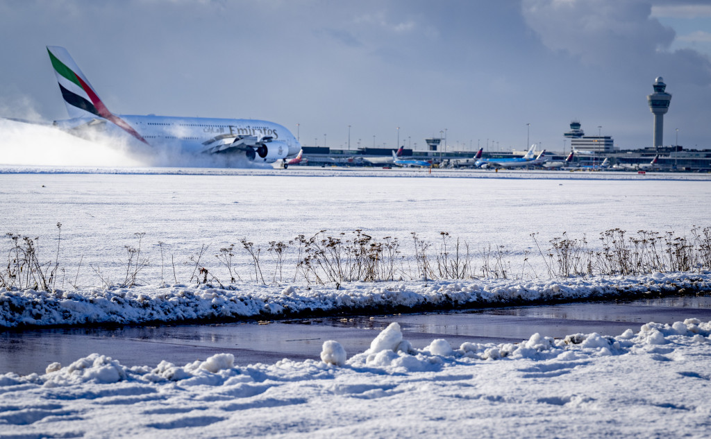 Een vliegtuig landt in de sneeuw op luchthaven Schiphol.