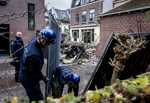 Politieagenten plaatsen zware hekken bij panden in de Visscherssteeg in het centrum, daags na een explosie die werd opgevolgd door een grote brand.
