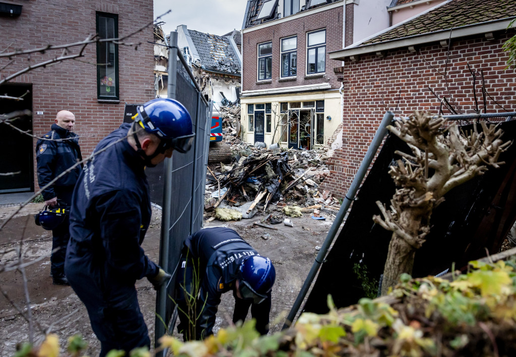 Politieagenten plaatsen zware hekken bij panden in de Visscherssteeg in het centrum, daags na een explosie die werd opgevolgd door een grote brand.