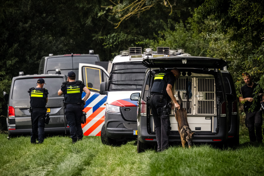 Het team Forensisch Technisch Onderzoek van de politie doet onderzoek met een speurhond in een weiland een dag na het schietincident in het Gelderse Overasselt.