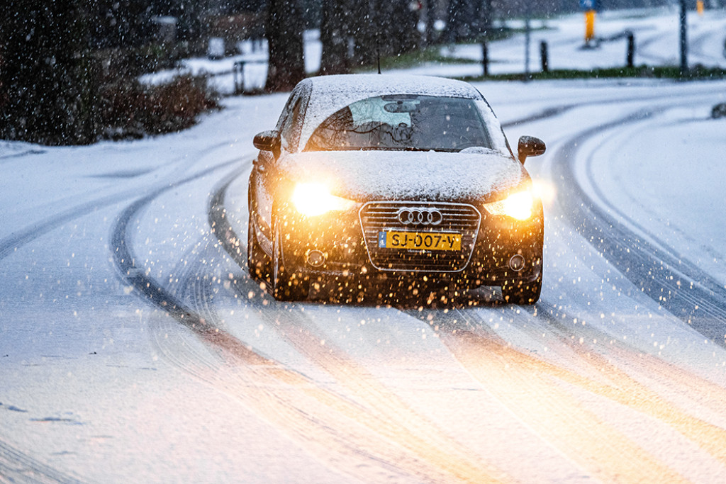 Auto's op een besneeuwde weg. In het hele land geldt code geel voor gladheid door sneeuw of bevriezing van wegen.